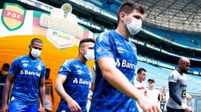 Des joueurs avec des masques en entrant sur le terrain, au Brésil