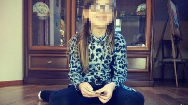  Berenyss a 7 ans, a les cheveux bruns longs, et porte une jupe à volants blancs et un haut multicolore.