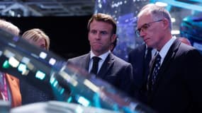 Le président français Emmanuel Macron regarde une voiture à côté du président de Peugeot et directeur général de Stellantis, Carlos Tavares, le premier jour du salon de l'auto de Paris, le 17 octobre 2022.
