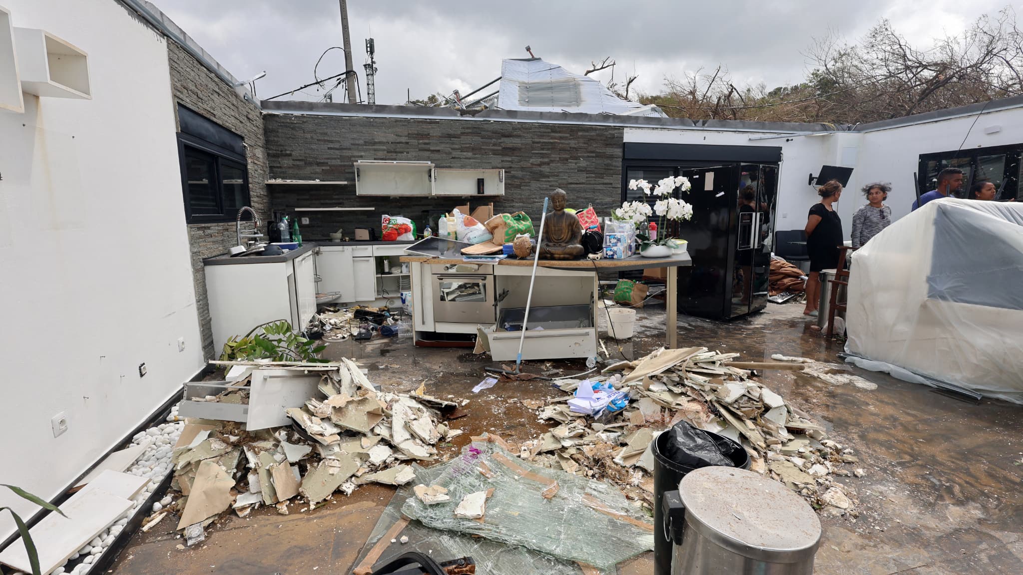 Des Réunionnais dans leur habitation endommagée dont le toit a été emporté par le cyclone à Saint-Benoit, sur l'île de La Réunion (France), dans l'océan Indien, le 1er mars 2025.