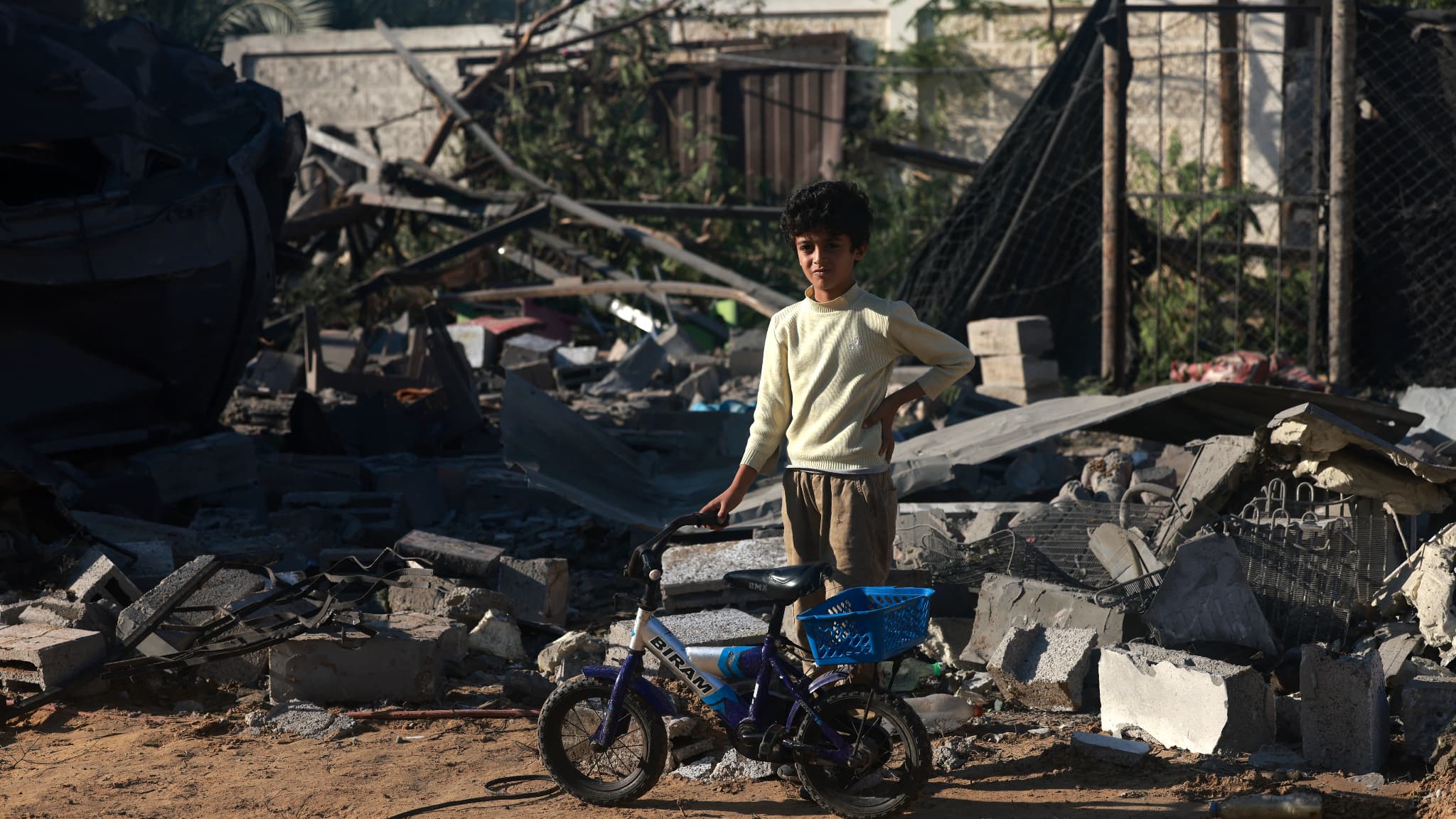 Un garçon palestinien se tient à côté de son vélo devant les débris d'une maison après une frappe israélienne à Rafah dans le sud de la bande de Gaza le 18 novembre 2023. 