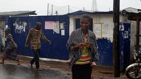 Des Libériens marchent devant l'ancienne école, transformée en centre d'isolement, d'où 17 malades se sont échappés.