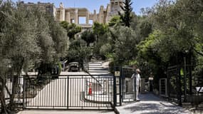 Un employé ferme le portail d'accès au site archéologique de l'Acropole à Athènes, le 14 juillet 2023.