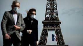 Homme et femme portant un masque devant la Tour Eiffel à Paris (photo d'illustration)