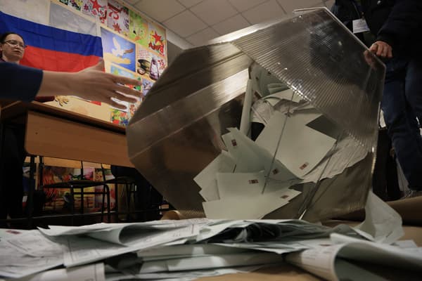 Des membres d'une commission électorale locale vident une urne dans un bureau de vote après la fermeture des bureaux de l'élection présidentielle russe à Simferopol, en Crimée, le 17 mars 2024.
