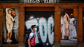 Un jeune homme passe devant un bar fermé à Madrid, en Espagne, le 9 juillet 2020