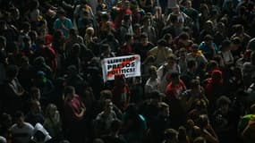 Un manifestant tient une pancarte disant "Libérez les prisonniers politiques", au milieu d'une foule à l'aéroport de Barcelone, le jour de l'annonce des peines d'indépendantistes catalans