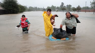 Des habitants de Houston se fraient un chemin dans leur quartier inondé, le 28 août 2017 à Houston (Texas).
