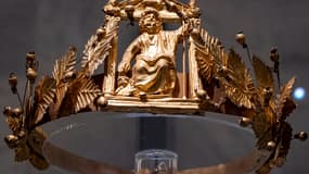 Cette photo, prise le 10 mai 2023, montre une couronne d'or ornée de feuilles et de branches de vigne, entourant une représentation du dieu Sérapis, entouré de bustes miniatures des divinités Isis et Harpocrate, sur la façade d'un temple datant du IIe siècle. Cette couronne fait partie du trésor de Douche (Dush), découvert en 1989 dans l'oasis de Kharga, caché dans le mur d'un fort romain. Elle est aujourd'hui exposée au Musée national de la civilisation égyptienne, dans le quartier de Fustat, au Caire.