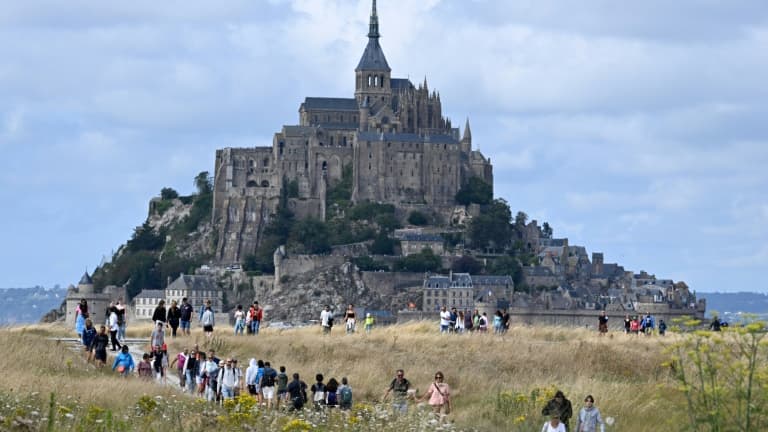 Des touristes marchent près du Mont-Saint-Michel, dans la Manche, le 25 juillet 2023