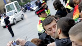 Un couple d'hommes s'embrasse au passage de la papamobile du pape Benoit XVI à Barcelone en Espagne le 7 novembre 2010.