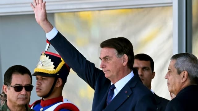 Le président brésilien Jair Bolsonaro (C) salue lors d'un défilé de véhicules militaires devant le palais du Planalto à Brasilia, le 10 août 2021