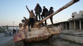 Des combattants anti-gouvernementaux posent pour une photo sur un char sur la route menant à Maaret al-Numan dans la province d'Idlib au nord-ouest de la Syrie, le 30 novembre 2024.
