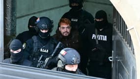 Le trafiquant de drogue français Mohamed Amra (c) escorté par des policiers hors de la Cour d'appel de Bucarest, le 23 février 2025 en Roumanie, au lendemain de son arrestation en vertu d'un mandat d'arrêt européen