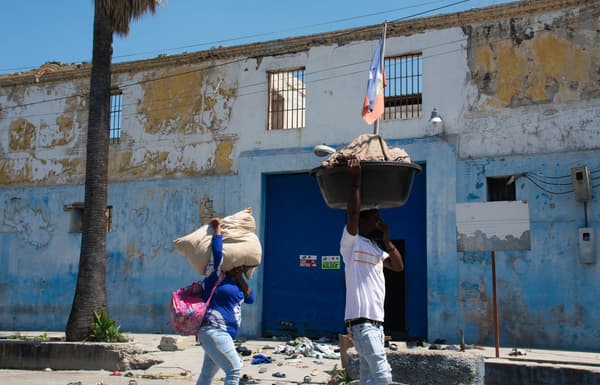 Des personnes marchent les mains sur le visage pour se protéger de la puanteur des corps en décomposition alors qu'elles passent devant le pénitencier national de Port-au-Prince, Haïti, 4 mars 2024.