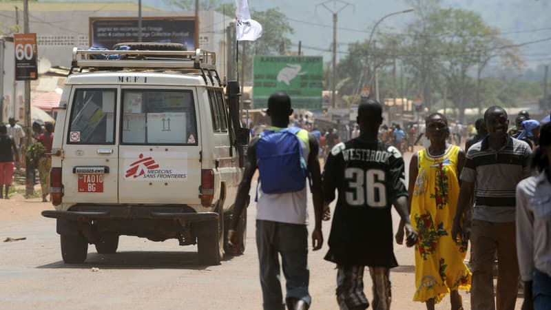 Des gens marchent près d'une voiture de Médecins Sans Frontières dans une rue de Bangui , le 28 mars 2013.