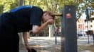 Une jeune femme tentant de se rafraîchir à une fontaine publique lors d'une vague de chaleur à Toulouse (Haute-Garonne) le 12 août 2025.