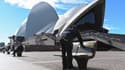 Un employé municipal nettoie les sièges publics à l'extérieur de l'Opéra de Sydney, le 26 juin 2021, après l'annonce des autorités d'un confinement de deux semaines.