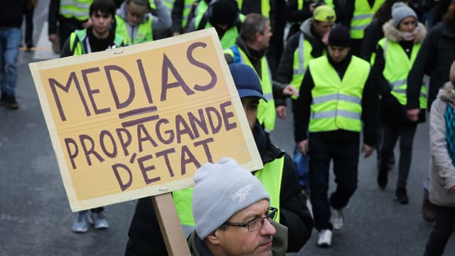 Un manifestant tient une pancarte "Médias = propagande d'Etat" le 12 janvier 2019 à Paris. 