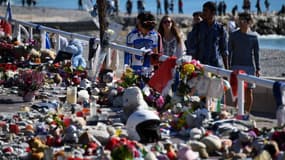 Des passants regardent des fleurs et bougies déposées en mémoire des victimes de l'attentat du 14 juillet 2016 à Nice, le 15 octobre suivant. (Photo d'illustration)