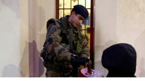 Un enfant offre un part de gâteau à un soldat devant une synagogue à Neuilly-sur-Seine, le 21 janvier 2014.