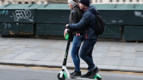 Deux usagers sur une trottinette Lime dans les rues de Paris en mars 2019.