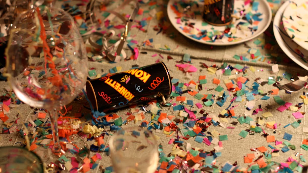 Une table de fête recouverte de confettis et de cotillons. 