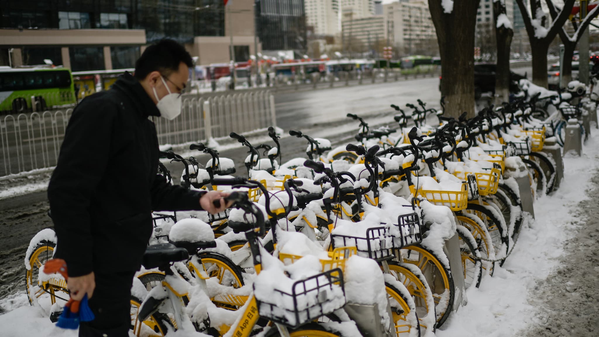 Un homme loue un vélo couvert de neige à Pékin le 21 février 2024.