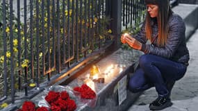 Une jeune femme allume une bougie devant l'ambassade russe à Kiev, en hommage aux victimes du crash de l'Airbus en Egypte, samedi.
