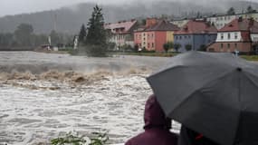 Des passants sous un parapluie observent le fleuve Biala alors que des inondations frappent l'Europe centrale, à Glucholazy, en Pologne, le 14 septembre 2024