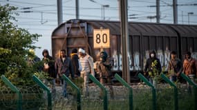 Des migrants ayant réussi à traverser le terminal Eurotunnel marchent sur les voies, dans le nord de la France, essayant de rejoindre une navette pour se rendre en Angleterre, le 28 juin 2015.