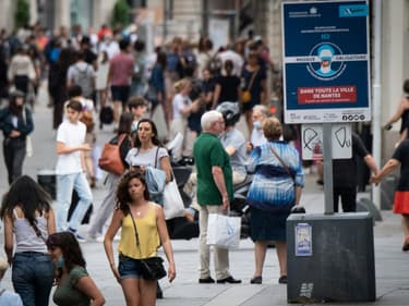 Des passants marchent près d'un panneau exigeant le port du masque à Nantes (France), le 17 juin 2021.