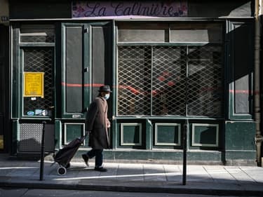 Un passant devant un magasin fermé --car ne faisant pas partie des commerces dits non essentiels--, à Paris le 20 mars 2021