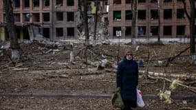 Une femme se tient près d'un immeuble détruit, près de Kiev, en Ukraine, le 37 février 2022.