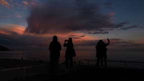 Des personnes prennent des photos au coucher du soleil sur la Promenade des Anglais à Nice, le 26 mars 2025. (photo d'illustration)