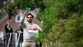 Le manifestant Salwan Momika brandit le livre saint musulman et une feuille de papier montrant le drapeau irakien lors d'une manifestation devant l'ambassade d'Irak à Stockholm, en Suède, le 20 juillet 2023.