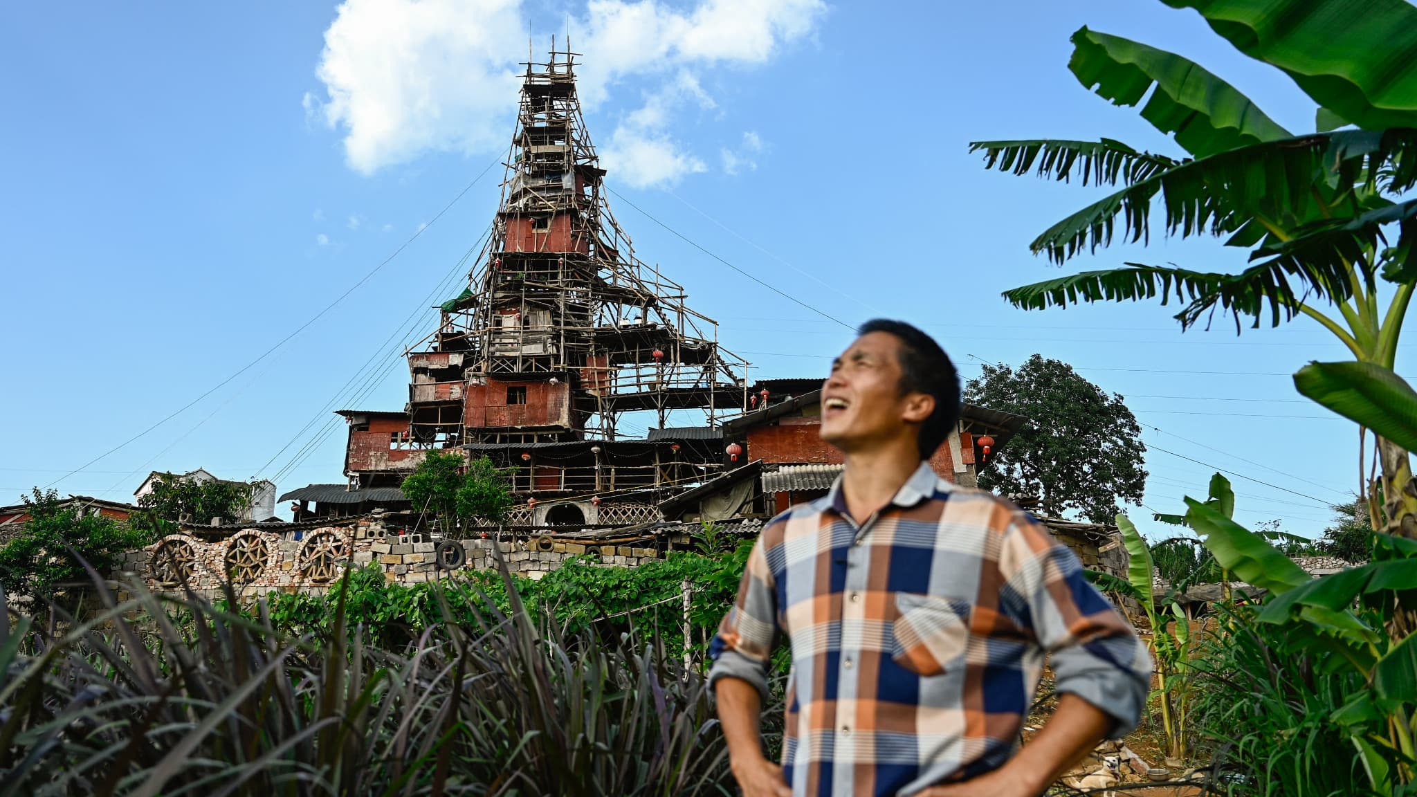 Cette photo prise le 20 mai 2025 montre Chen Tianming devant sa maison étiquetée comme la plus étrange "maison-clou" de Chine -des foyers qui refusent de déménager face à des plans de développement- à Xingyi, dans la province de Guizhou, au sud-ouest du pays.