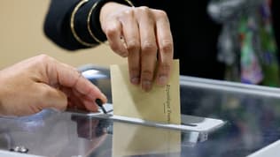 Une électrice glisse son bulletin dans une urne.