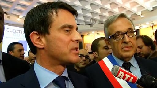 Manuel Valls, accompagné de Francis Chouat, son successeur à la mairie d'Evry, portant l'écharpe républicaine.