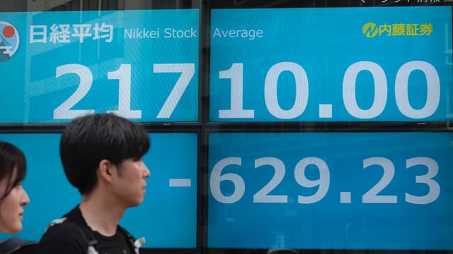 Image d'illustration - Des piétons passent devant un écran retransmettant la cotation à la Bourse de Tokyo au Japon.