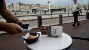 Un homme portant un masque de protection passe à côté de la terrasse d'un café sur le Vieux Port, le 2 juin 2020 à Marseille.
