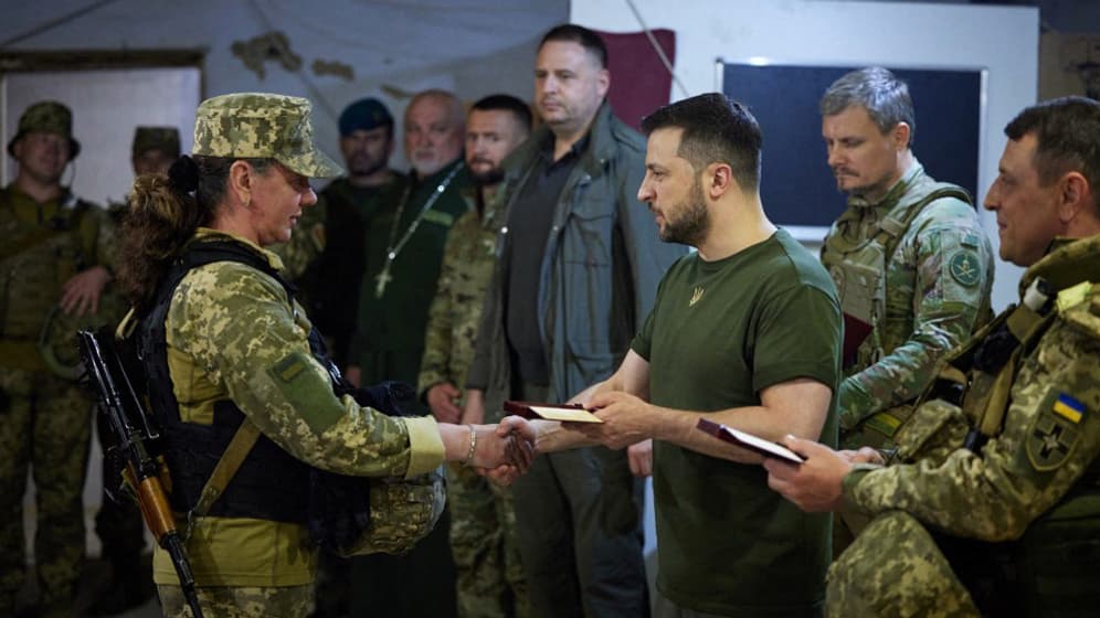 Le président ukrainien Volodymyr Zelensky remet une récompense à une combattante ukrainienne lors de sa visite à Mykolaïv dans le sud du pays le 18 juin 2022. Le président ukrainien Volodymyr Zelensky remet une récompense à une combattante ukrainienne lors de sa visite à Mykolaïv dans le sud du pays le 18 juin 2022.