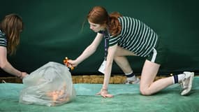 Des ramasseuse de balles ramassent des confettis oranges jetés par des militants écologistes de Just Stop Oil