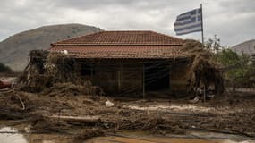 Cette photo prise le 26 septembre 2023 montre une maison endommagée à côté de laquelle flotte le drapeau national grec après le retrait des eaux de la tempête Daniel, dans le village de Vlochos, dans le centre de la Grèce