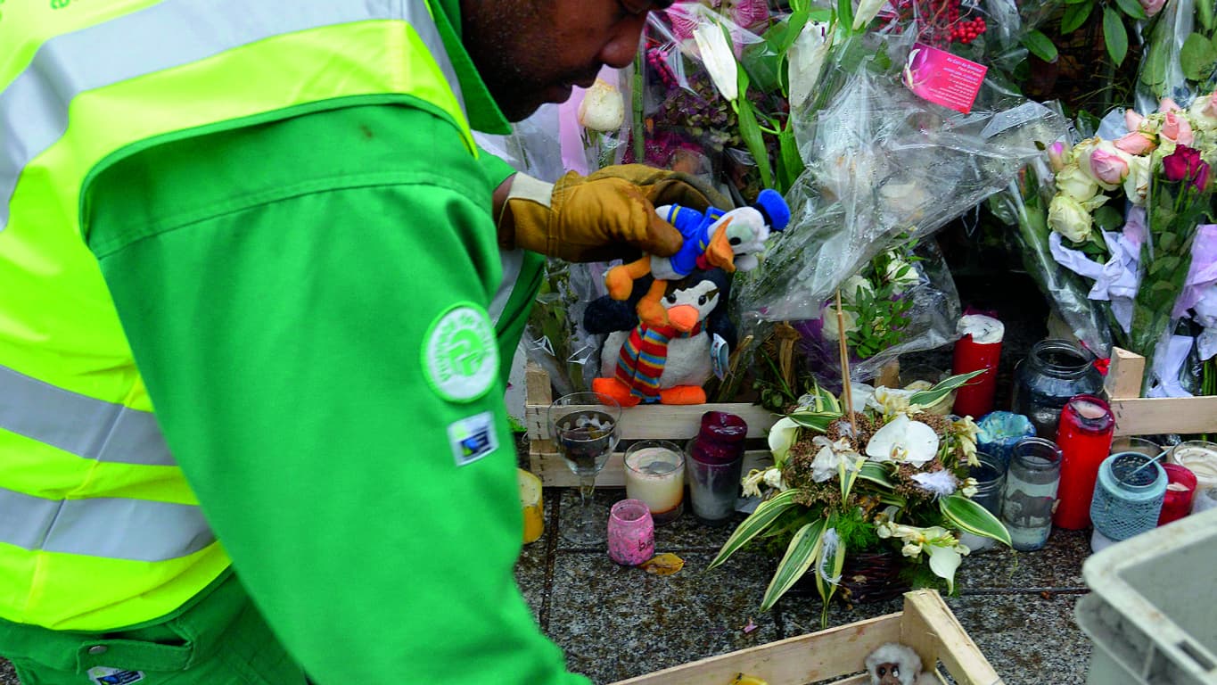 Un employé de la mairie collectant des objets d'un mémorial en face du Bataclan, le 10 décembre 2015