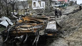 Des habitants passent près d'un tank russe détruit dans le village de Zalissya (Ukraine), au nord-est de Kiev, le 19 avril 2022