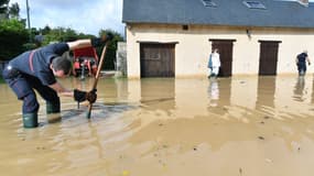 Un pompier tente de déboucher une bouche d'égout devant une maison inondée après le passage de la dépression Kirk, à Coltainville près d'Epernon, le 10 octobre 2024