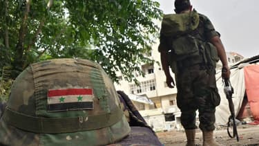 Un soldat syrien posté près d'un casque orné d'un drapeau syrien, à Homs, le 27 mai 2014.