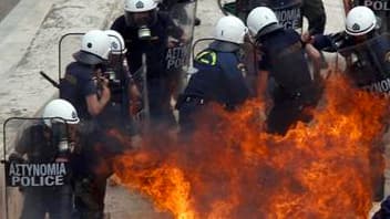 Policiers grecs cibles d'un cocktail molotov près du Parlement à Athènes, mercredi. Selon les services de pompiers, trois personnes sont mortes dans un immeuble incendié par des protestataires dans la capitale grecque lors de la manifestation contre le pl