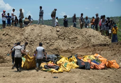 Des corps sont transportés dans une fosse commune avant une cérémonie funéraire pour les victimes du séisme à Palu sur l'île des Célèbes en Indonésie, le 1er octobre 2018 Des corps sont transportés dans une fosse commune avant une cérémonie funéraire pour les victimes du séisme à Palu sur l'île des Célèbes en Indonésie, le 1er octobre 2018